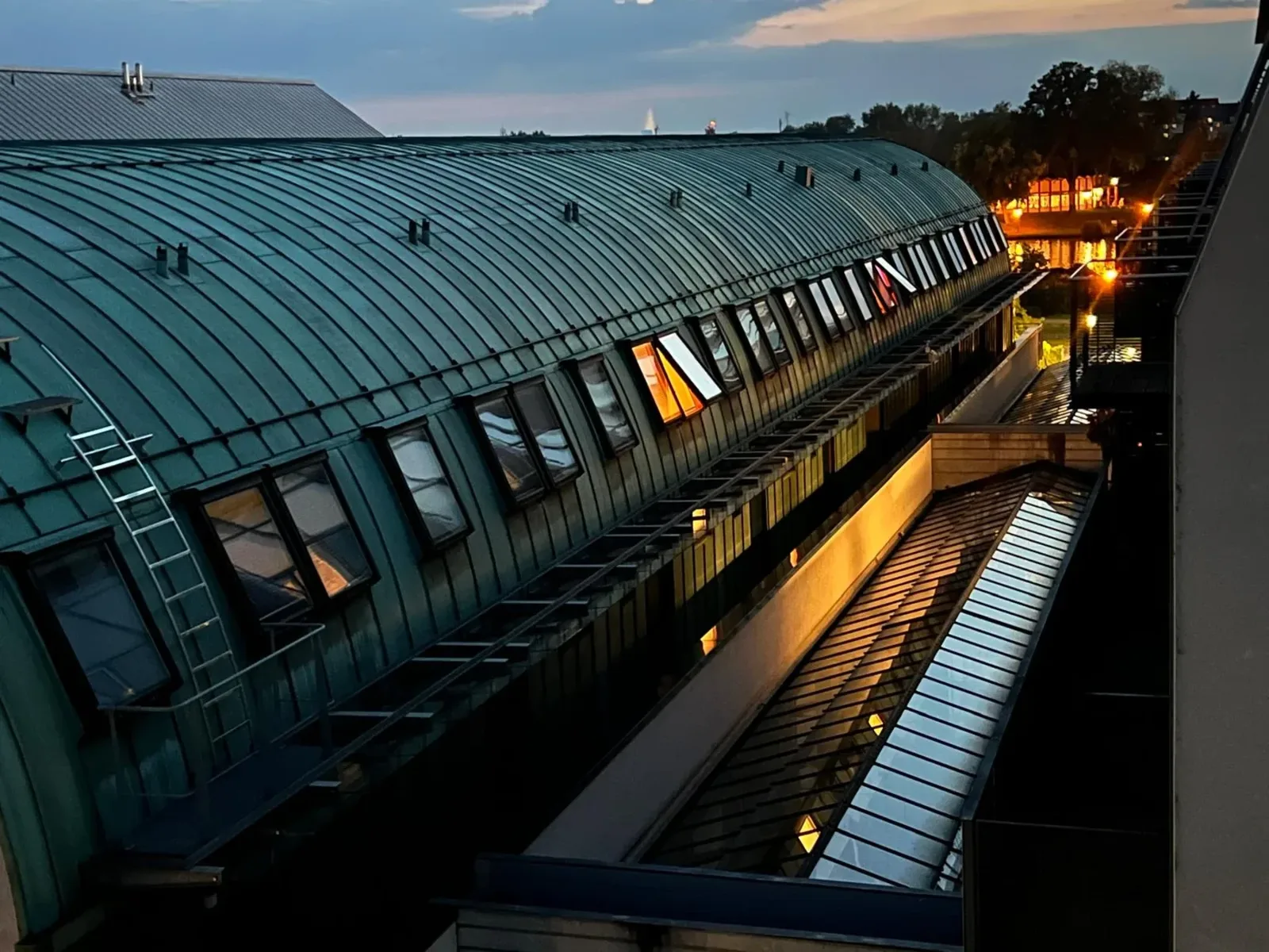 Kupferdach der KLIA Passage über den beleuchteten Fenstern in der Dämmerung