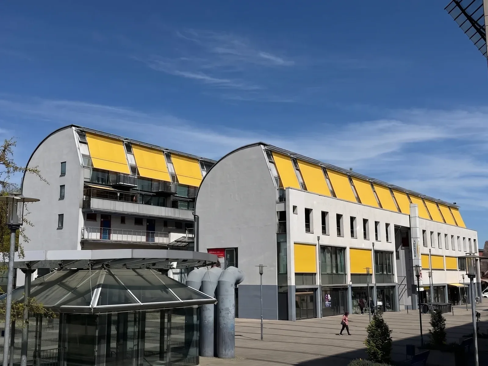 Passagengebäude mit gelben Markisen und gläsernem Pavillon